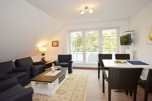 A modern living room with a sofa set, a coffee table, and a dining area with chairs and a table. - Holiday apartment with 2 bedrooms (Norden-Norddeich)