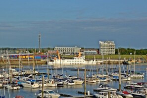 Ein Yachthafen mit mehreren vertäuten Booten, einem großen weißen Schiff und Gebäuden im Hintergrund.