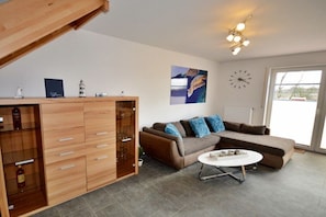 Ein modernes Wohnzimmer mit einer Eckcouch, einem Couchtisch und einer Holzkabine.