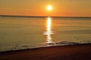 Ein Strand bei Sonnenuntergang über dem Wasser.