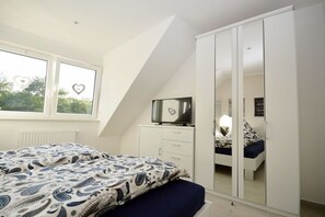 Ein Schlafzimmer mit einem Bett, einem Kleiderschrank, einem Fernseher und einem Fenster mit herzförmigen Verzierungen.