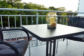 Ein Balkon mit Tisch, Korbstühlen und einem Einmachglas mit Brot.