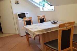 A dining area with a table, chairs, a microwave, and a small refrigerator. - near Warnemünde (Rostock) (Admannshagen-Ausbau)
