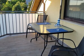 A balcony with a table and chairs, a glass of water, and a small blue and white striped object. - near Warnemünde (Rostock) (Admannshagen-Ausbau)