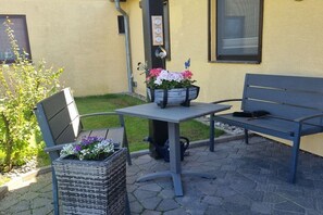 A patio with a table and bench, a potted plant, and a wall-mounted clock. - near Warnemünde (Rostock) (Admannshagen-Ausbau)