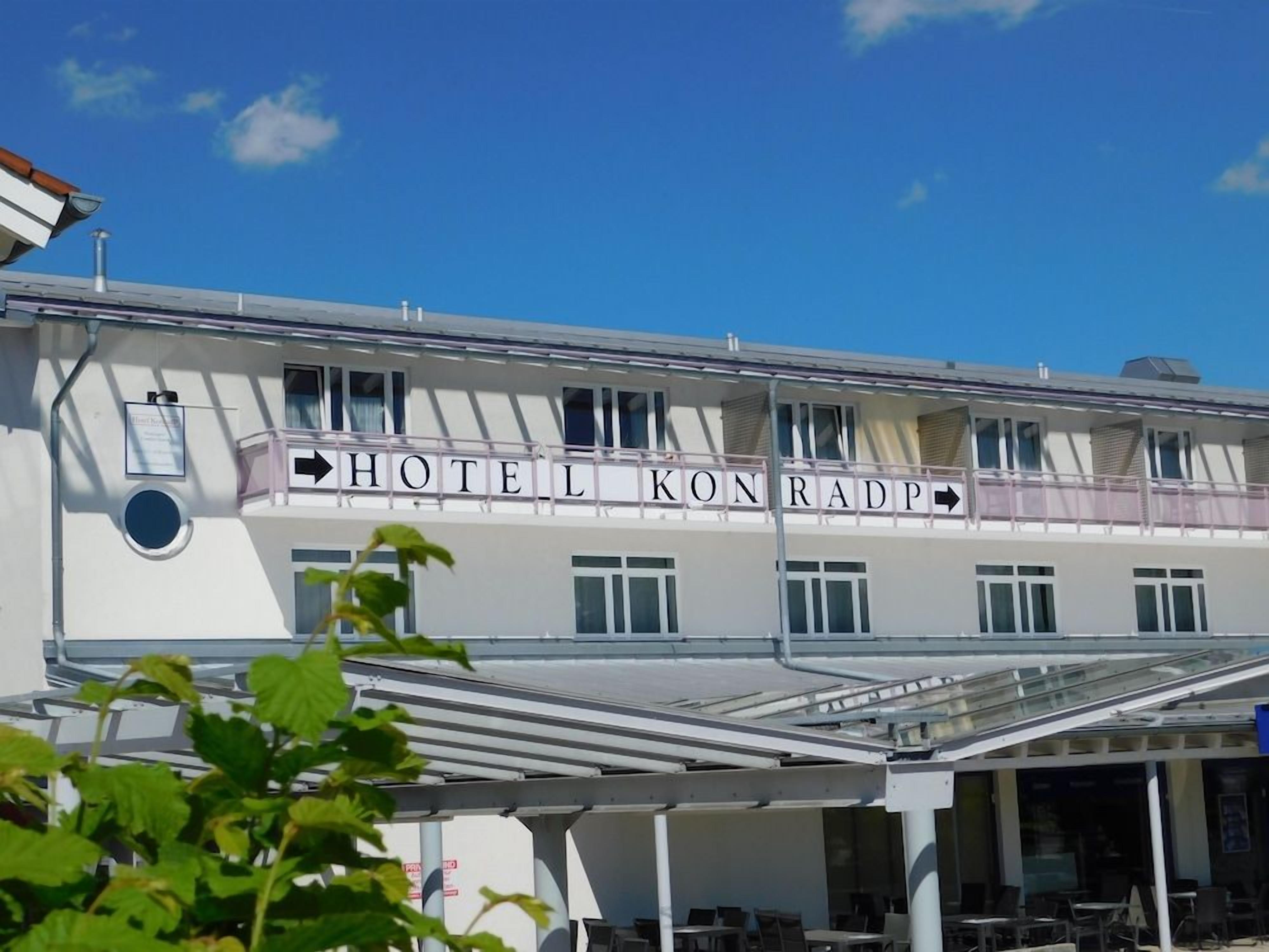 A hotel with a sign reading 'HOTEL KONRADP' and a covered outdoor seating area.