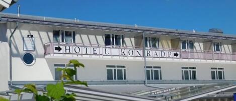 A hotel with a sign reading 'HOTEL KONRADP' and a covered outdoor seating area.