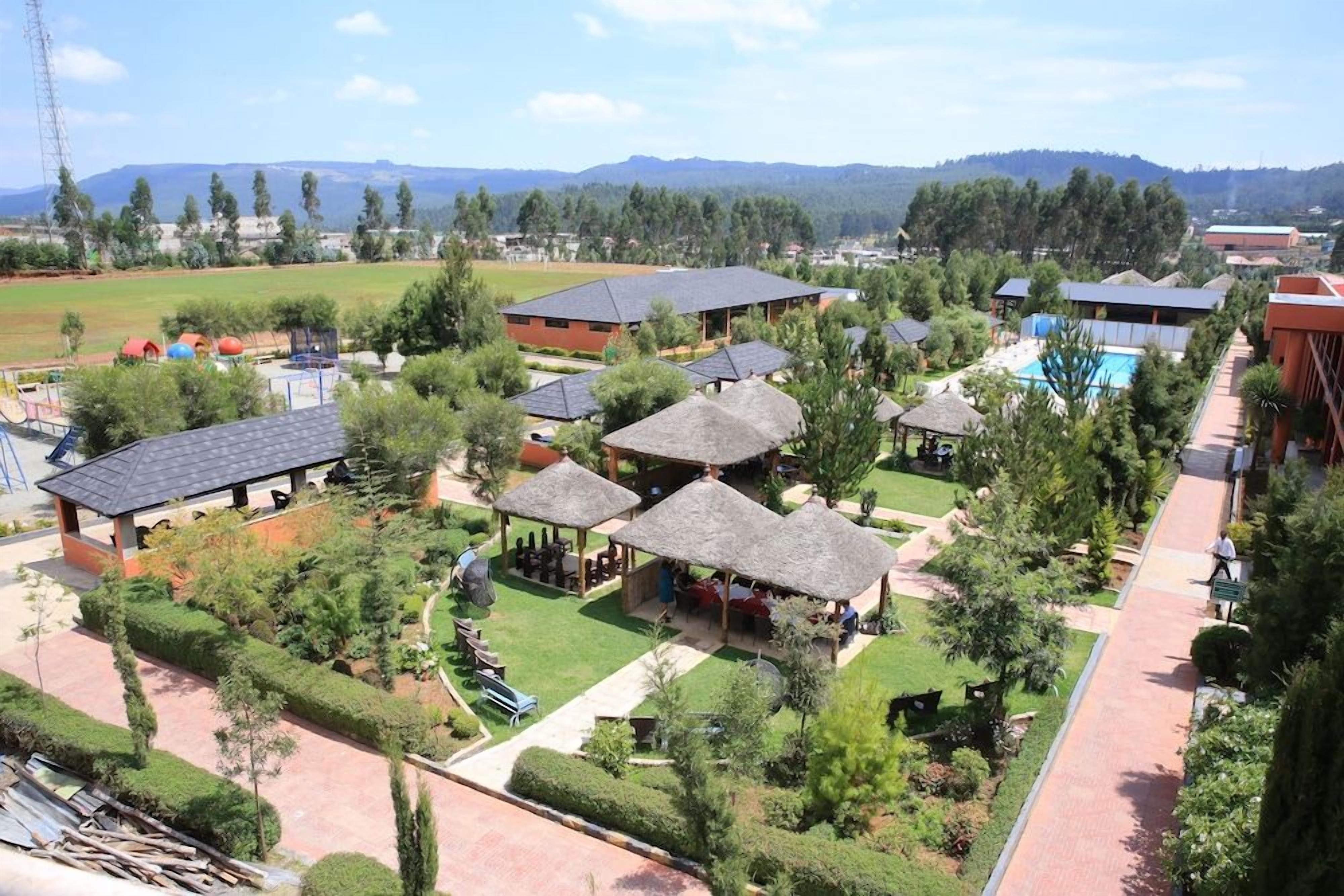 A resort with multiple buildings, outdoor seating areas, and a swimming pool.