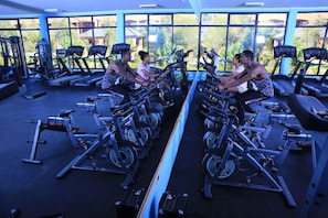 A gym with multiple exercise bikes and treadmills, large windows, and various fitness equipment. - Yaya Africa Athletics Village (Addis Ababa)