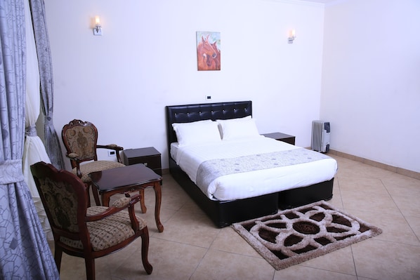 A bedroom with a bed, a chair, a table, and a rug. - Yaya Africa Athletics Village (Addis Ababa)
