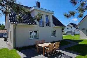 A two-story house with a balcony, a paved driveway, and a well-maintained lawn. - Holiday home with 2 bedrooms (Ostseebad Prerow)
