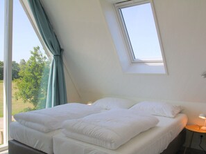 Ein Schlafzimmer mit Bett, Fenster und Nachttisch mit Lampe.
