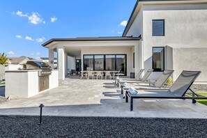 Eine moderne Außenpatio mit Lounge-Möbeln, einem Grill und einer überdachten Sitzgruppe.