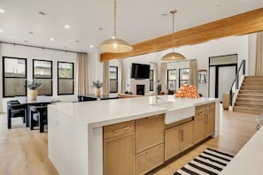 A modern kitchen with a large island, wooden cabinets, and pendant lighting. - Modern Manor-6BR, Pool&Spa, Air Hockey, Ping Pong (Scottsdale)