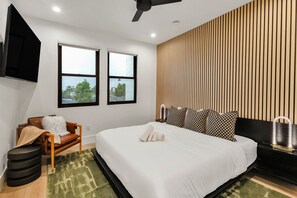 A modern hotel room with a large bed, a sofa, a TV, and a window with a view of trees. - Modern Manor-6BR, Pool&Spa, Air Hockey, Ping Pong (Scottsdale)