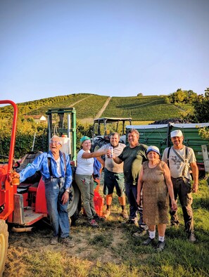 Un groupe de personnes se tient dans un paysage rural, avec un tracteur et une remorque en arrière-plan.