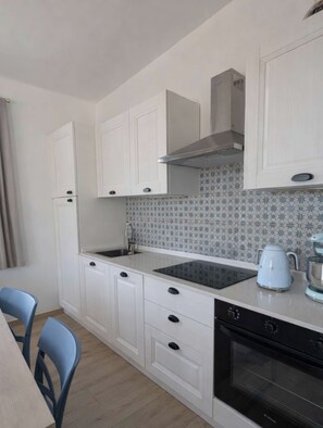 A compact kitchen with white cabinets, a black stove, and a patterned backsplash. - Casa dei Leoni - Adults-Only Sanctuary in Piedmont - Foxy (Piemonte)