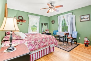 Ein Schlafzimmer mit einem Bett, einem Schreibtisch, einem Stuhl, einem Deckenventilator und einer kleinen Santa-Figur.