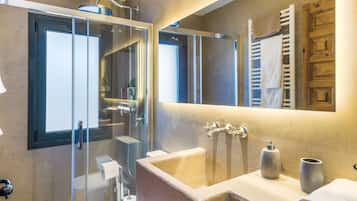 Un baño moderno con ducha envuelta en vidrio, un espejo grande y un lavabo con toallero.