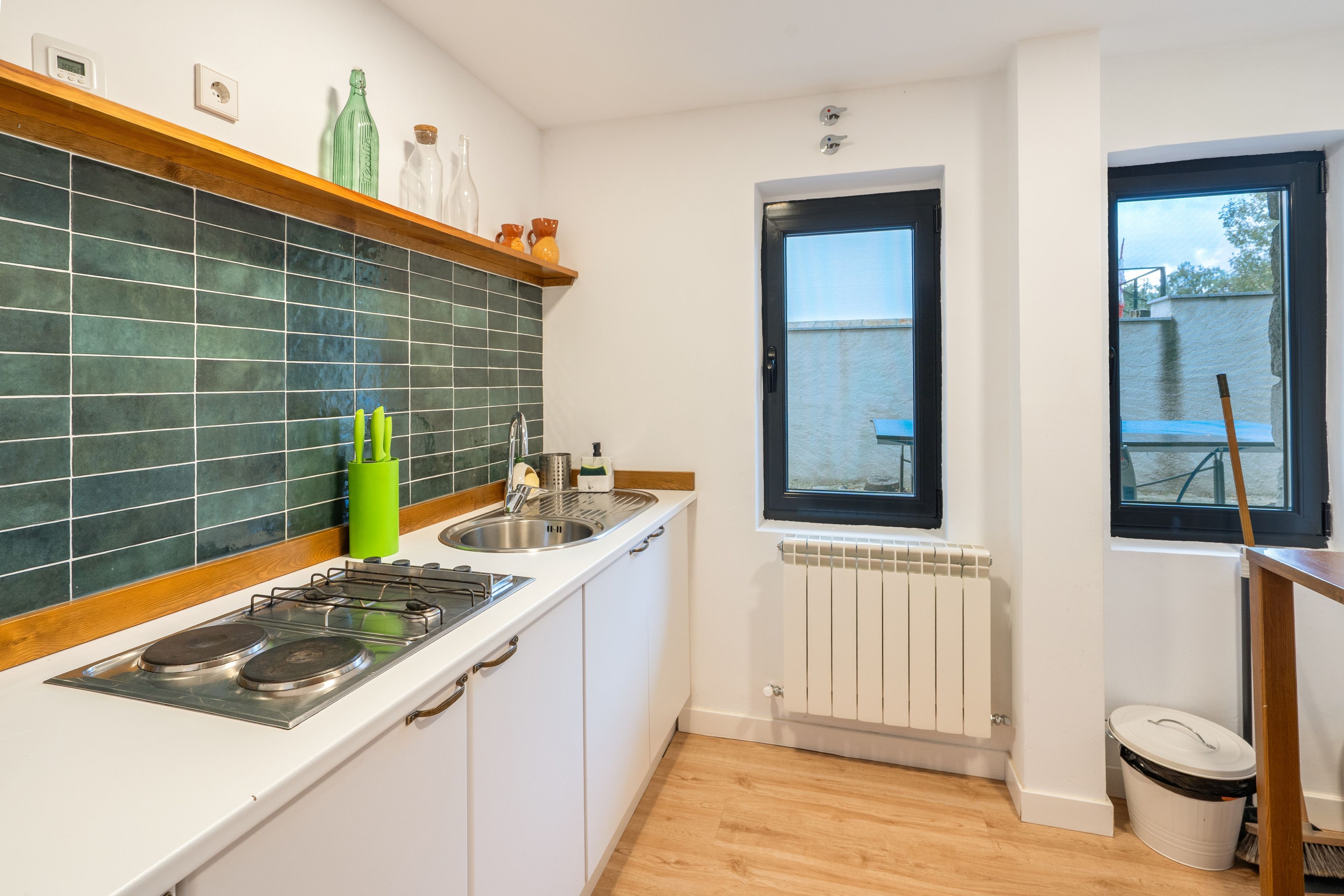Eine kleine Küche mit Gaskochfeld, Spüle und Fenster.