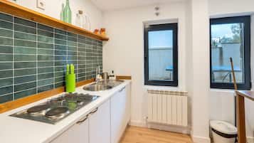Eine kleine Küche mit Gaskochfeld, Spüle und Fenster.