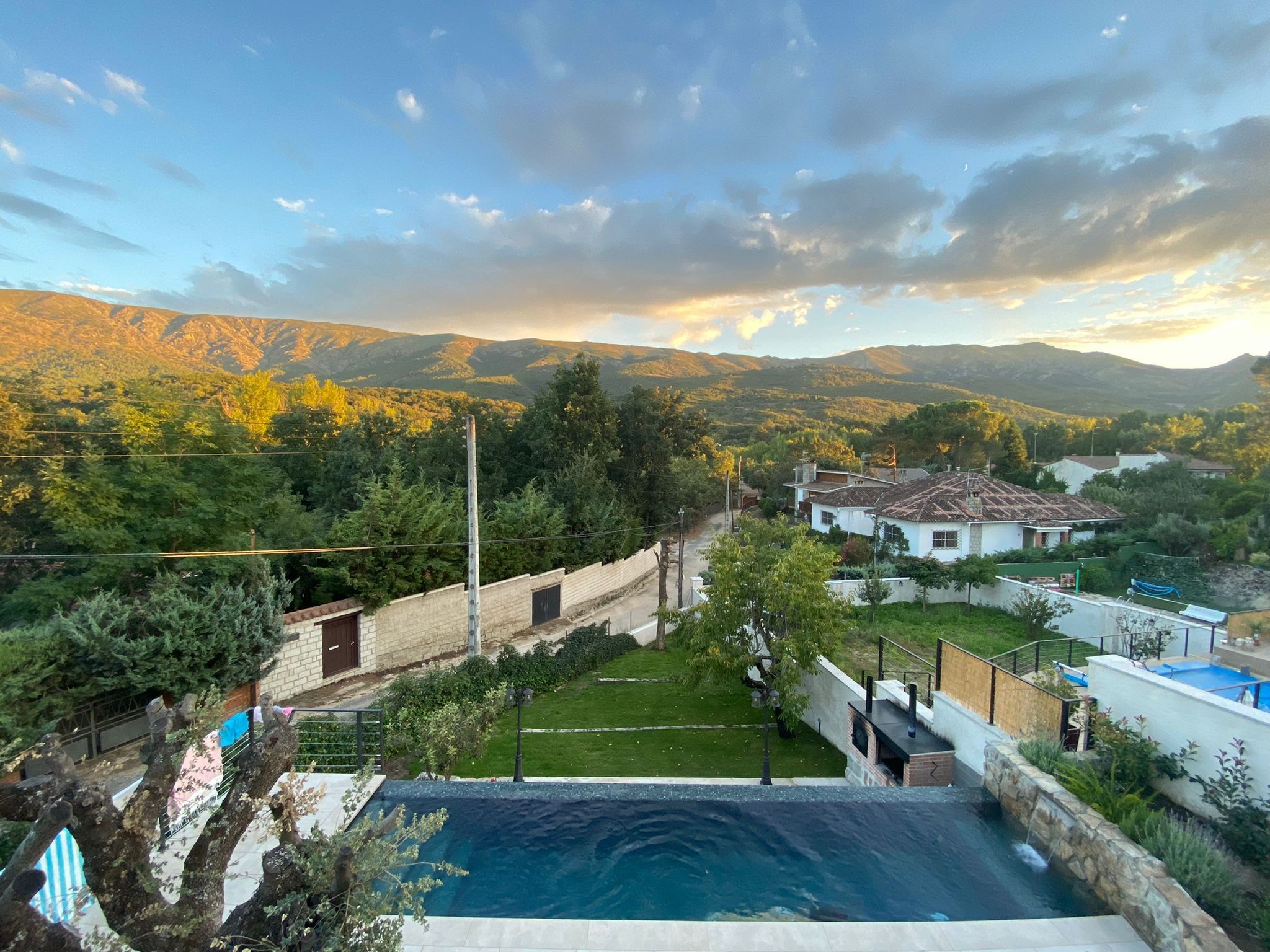Zona residencial con piscina, casas y montañas al fondo.