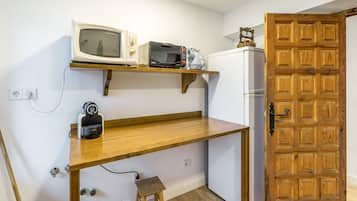 A compact kitchen with a wooden countertop, a microwave, a toaster, and a refrigerator.