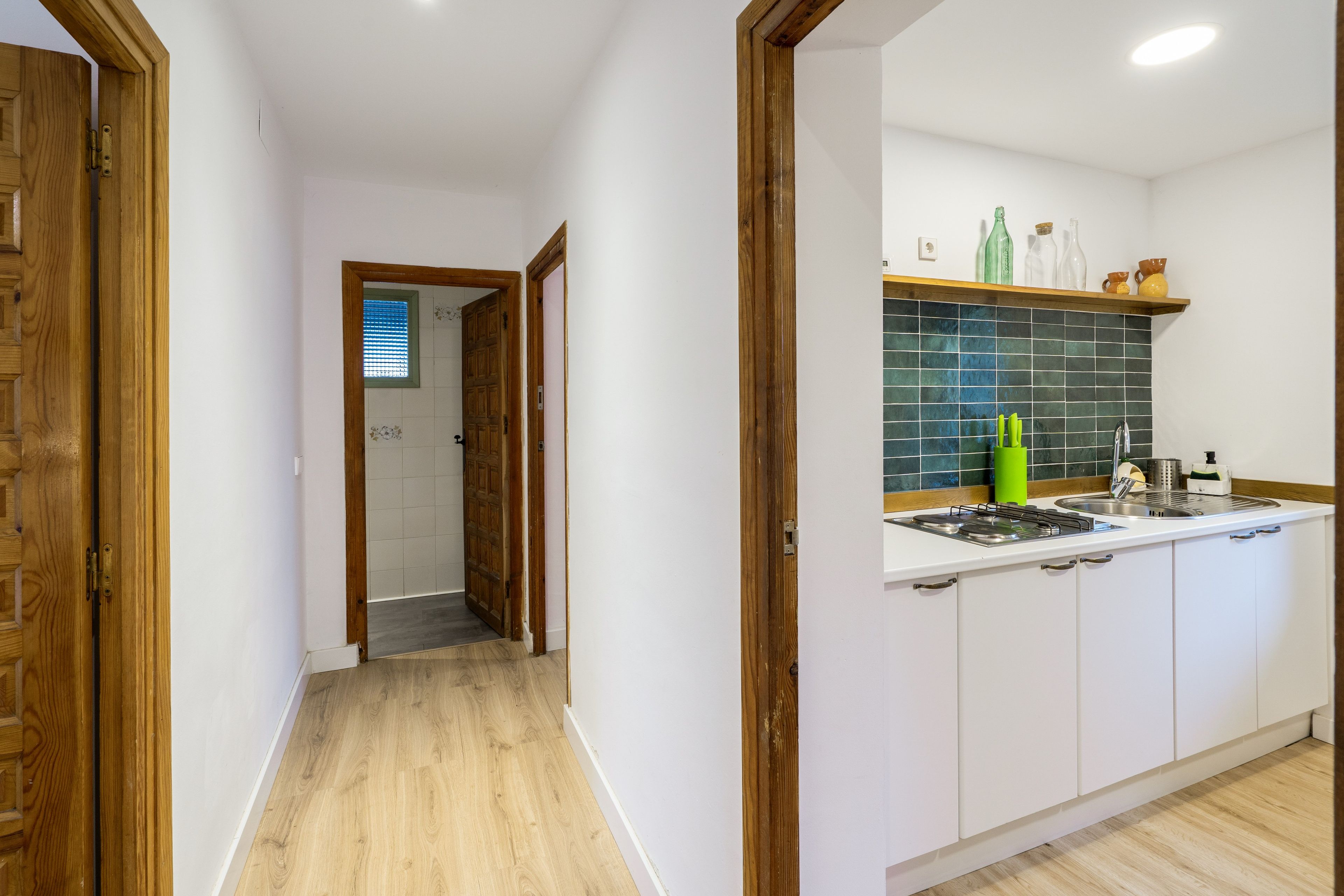 Een moderne keuken met witte kastjes, een betegelde achterwand en een roestvrijstalen spoelbak.