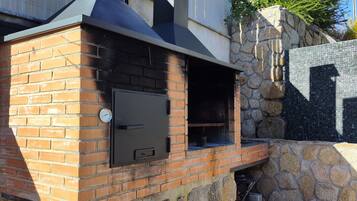 Un horno de ladrillo al aire libre con una pared de piedra y una chimenea de metal.