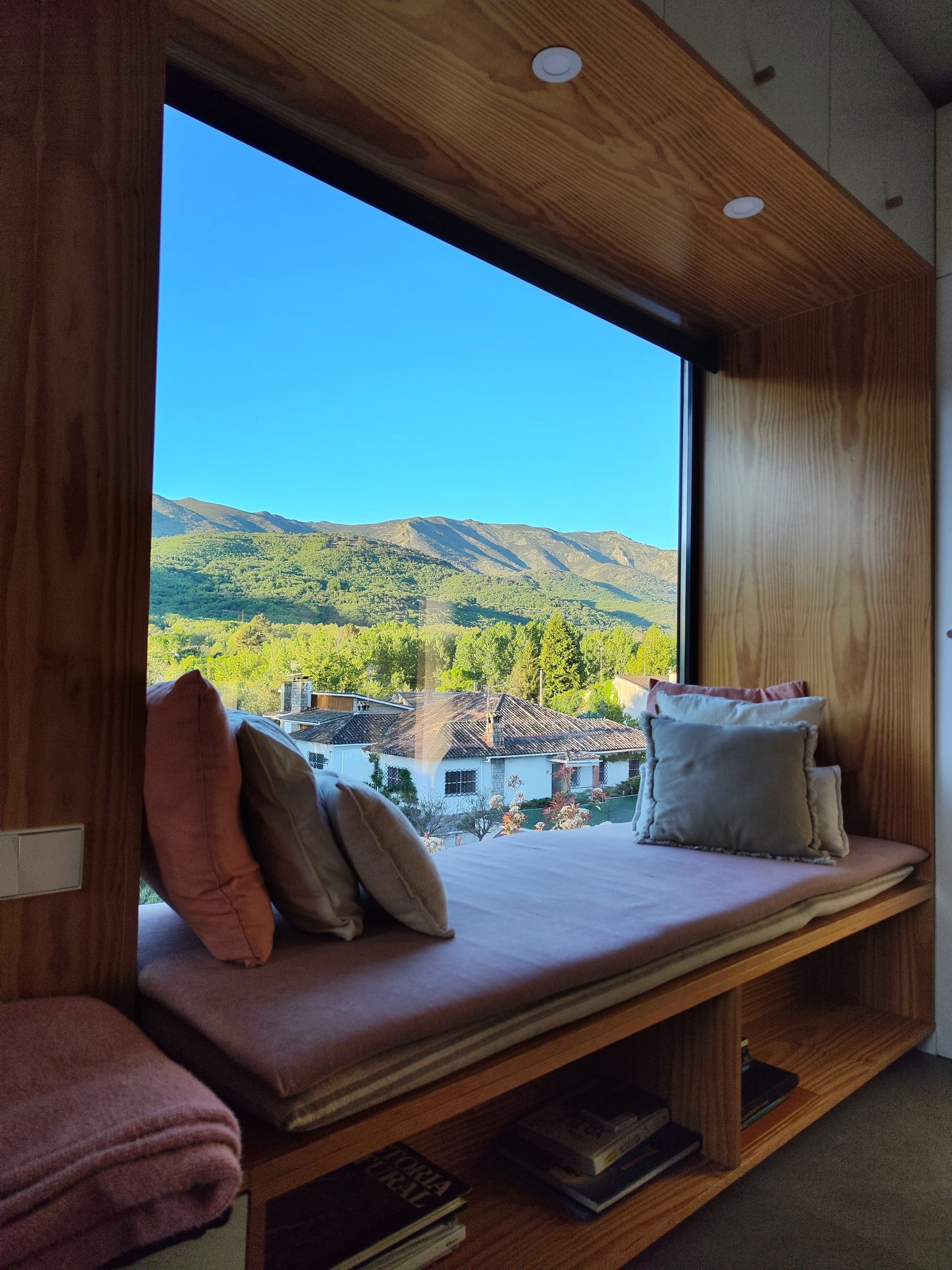 Een kamer met een groot raam met uitzicht op een bergachtig landschap.