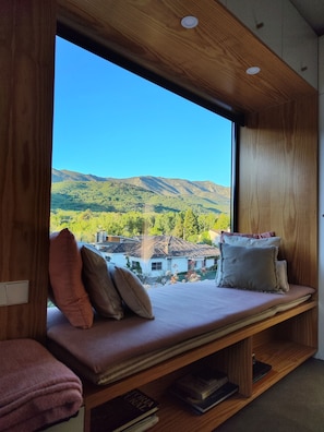 Een kamer met een groot raam met uitzicht op een bergachtig landschap.