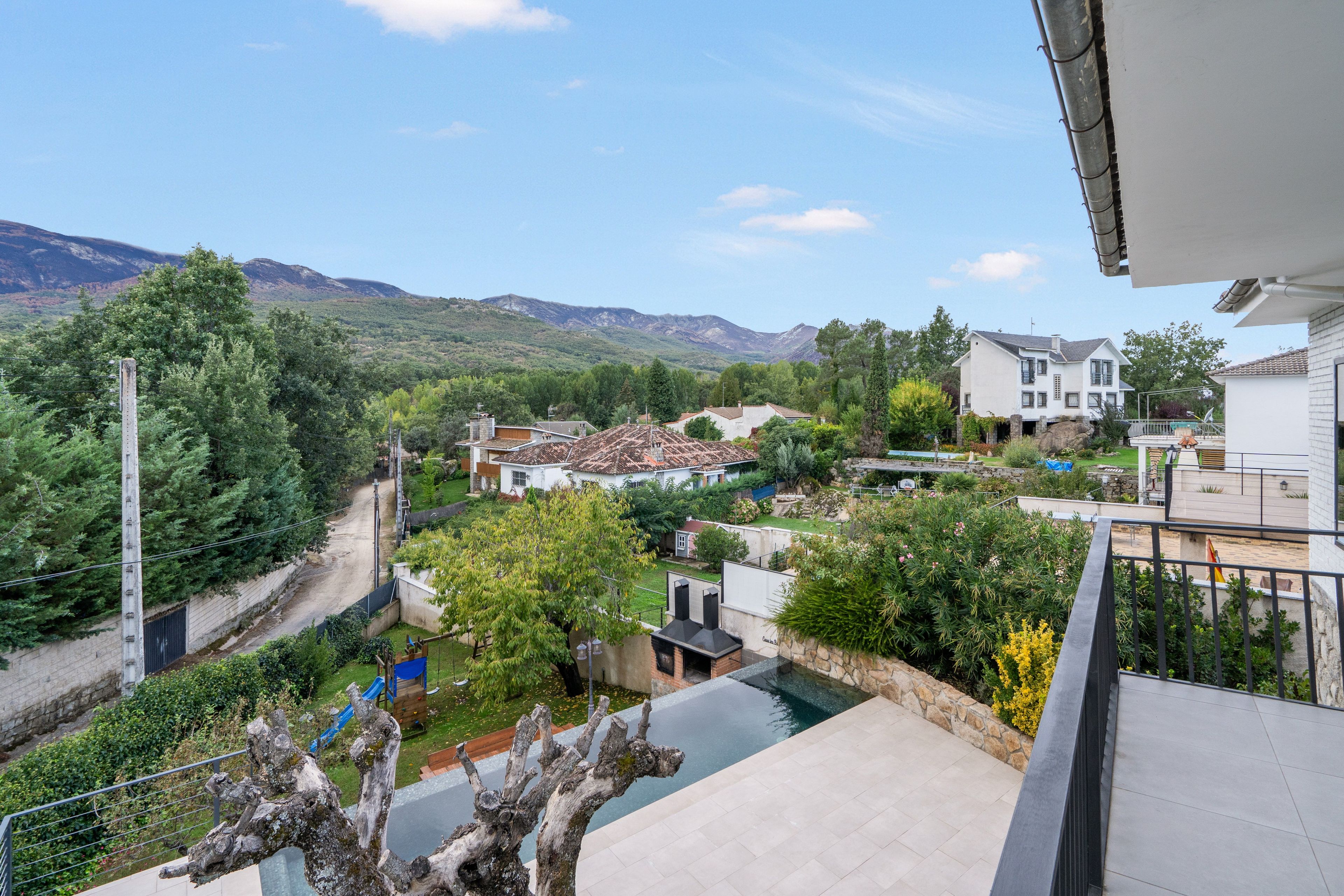 A residential area with houses, a swimming pool, and a mountain backdrop.