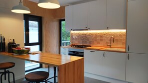 Una cocina moderna con encimera de madera, electrodomésticos de acero inoxidable y vistas al exterior.