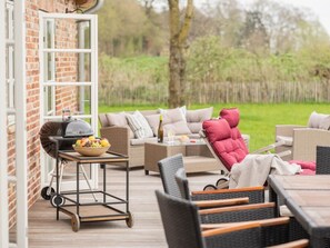 Ein Sitzbereich im Freien mit Grill, Tisch, Flasche und Obstschale.