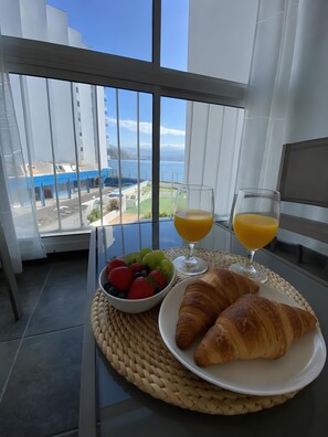Ein Balkon mit Frühstücksangebot, darunter Croissants, eine Obstschale und Gläser Orangensaft.
