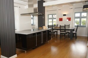 A modern kitchen with a central island, dark cabinetry, and a dining area with chairs and a table. - Holiday home with 3 bedrooms (Ostseebad  Prerow)