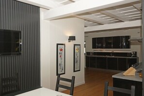 A modern kitchen with black cabinets, a white countertop, and a dining area with a table and chairs. - Holiday home with 3 bedrooms (Ostseebad  Prerow)