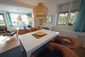 Un comedor moderno con una mesa blanca, sillas de mimbre y una lámpara colgante.