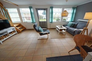 Ein Wohnzimmer mit einer Couch, Sesseln, einem Fernseher und einem Kamin.
