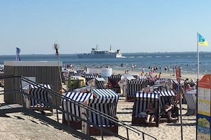 A beach with striped beach chairs and a ship in the background. - Majert's Dune Gold Norderney (Norderney)