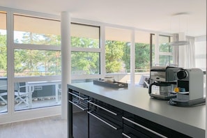 Eine moderne Küche mit großen Fenstern, einer Kaffeemaschine und einem Essbereich mit Sitzgelegenheiten im Freien.
