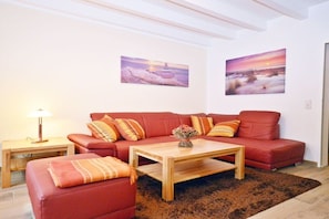 Ein Wohnzimmer mit einem roten Sofa, einem Holztisch und zwei Bildern an der Wand.