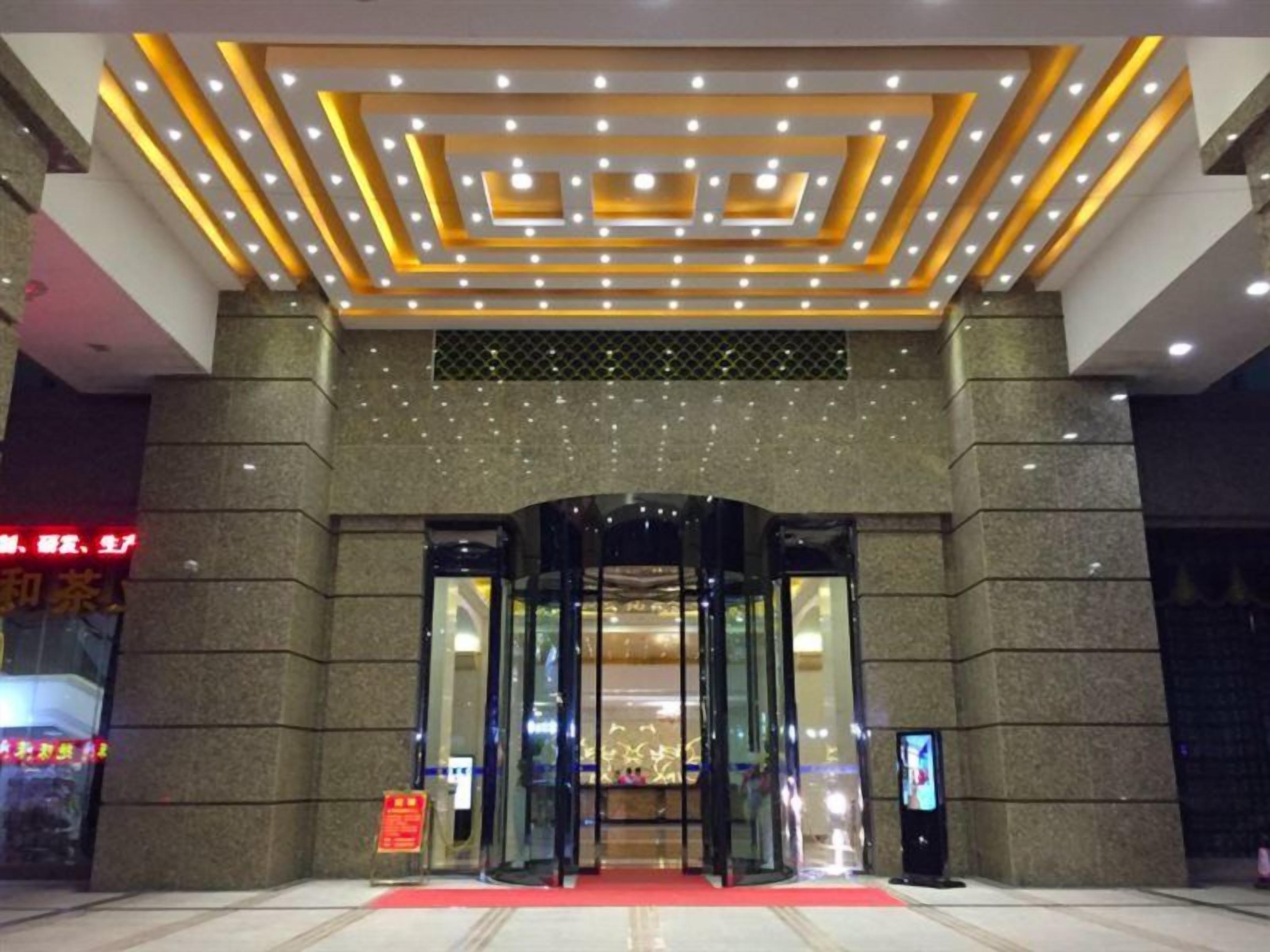 A hotel entrance with a revolving door, a red carpet, and a modern ceiling design.