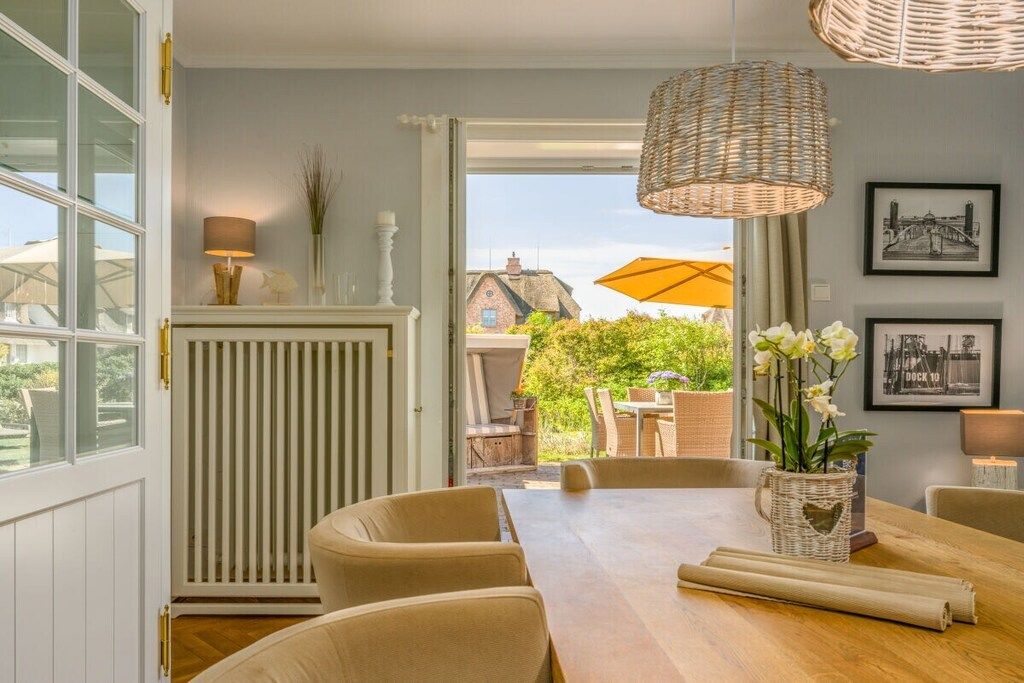 Un coin repas comprenant une table, des chaises et un luminaire suspendu en osier.