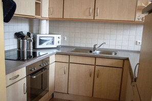 Eine kleine Küche mit Mikrowelle, Toaster, Spüle und Edelstahlgeräten.