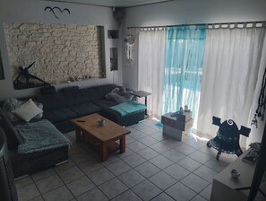 Ein Wohnzimmer mit Steinwand, einer Couch, einem Couchtisch und einem Fernseher-Lowboard.
