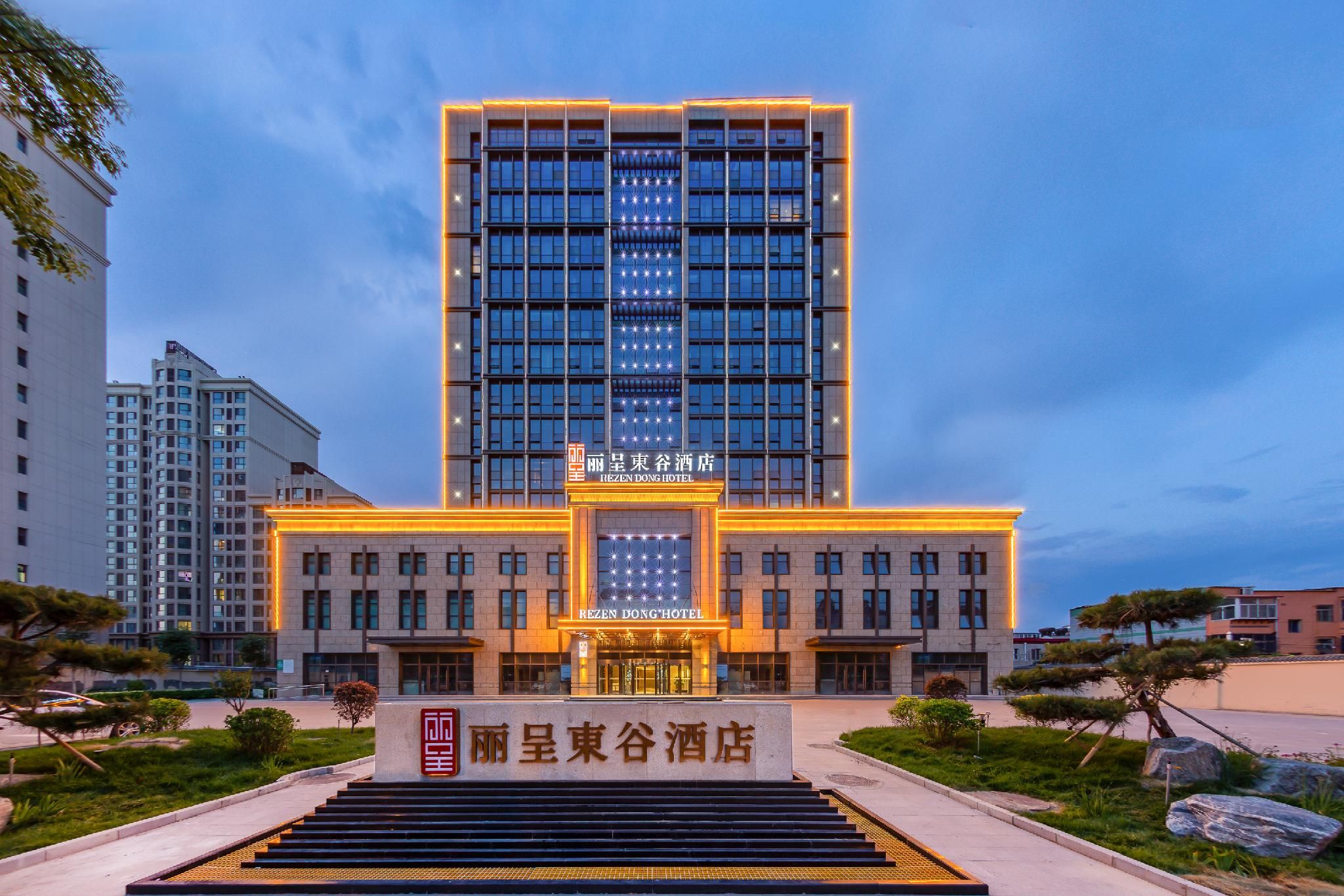 Un hôtel moderne, avec une entrée imposante, de nombreux étages et une façade bien éclairée.