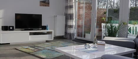 A modern living room with a flat-screen TV, white entertainment unit, and a coffee table.