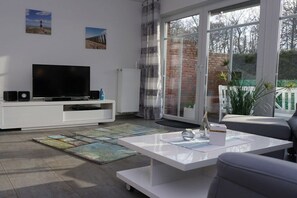 Een moderne woonkamer met een flatscreen televisie, een witte entertainmentkast en een salontafel.
