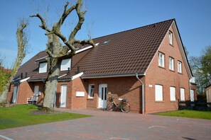Ein zweistöckiges Backsteinhäuschen mit Satteldach und einer Veranda, vor der ein Fahrrad abgestellt ist.